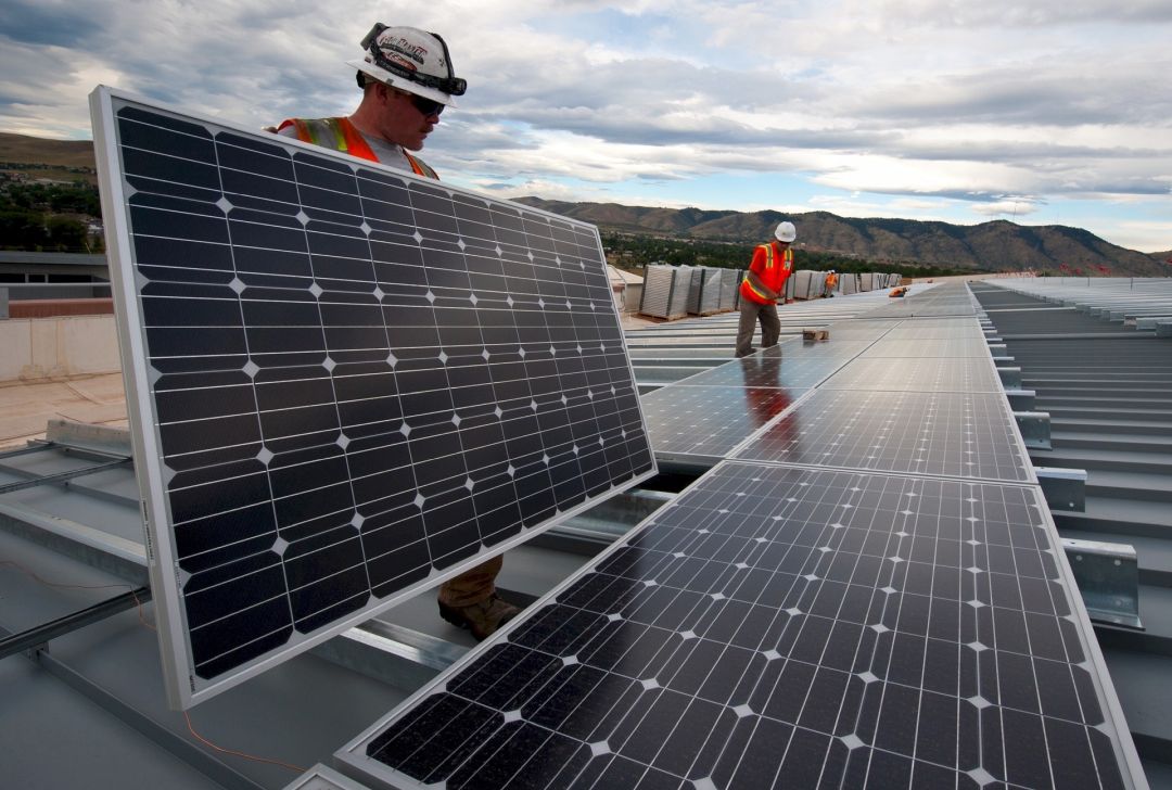 Technicians installing solar panels on a commercial roof.