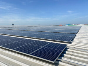 Solar panels installed in the metal roof of a large industrial building.