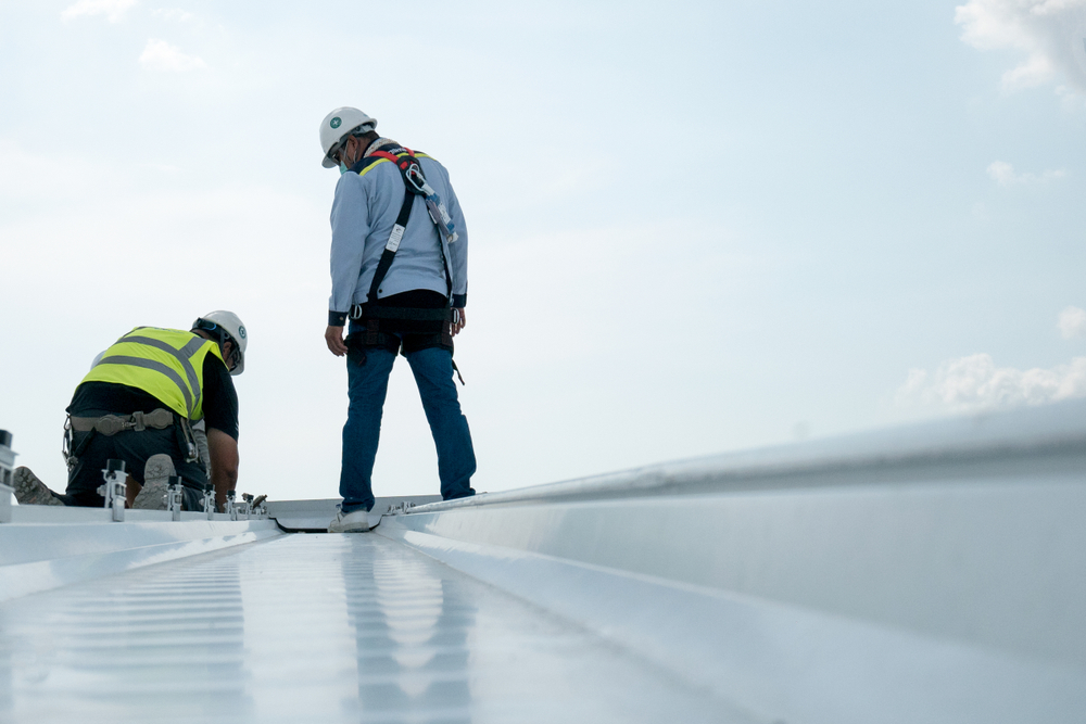 Engineers wearing safety uniforms conduct a roof inspection at a construction site.