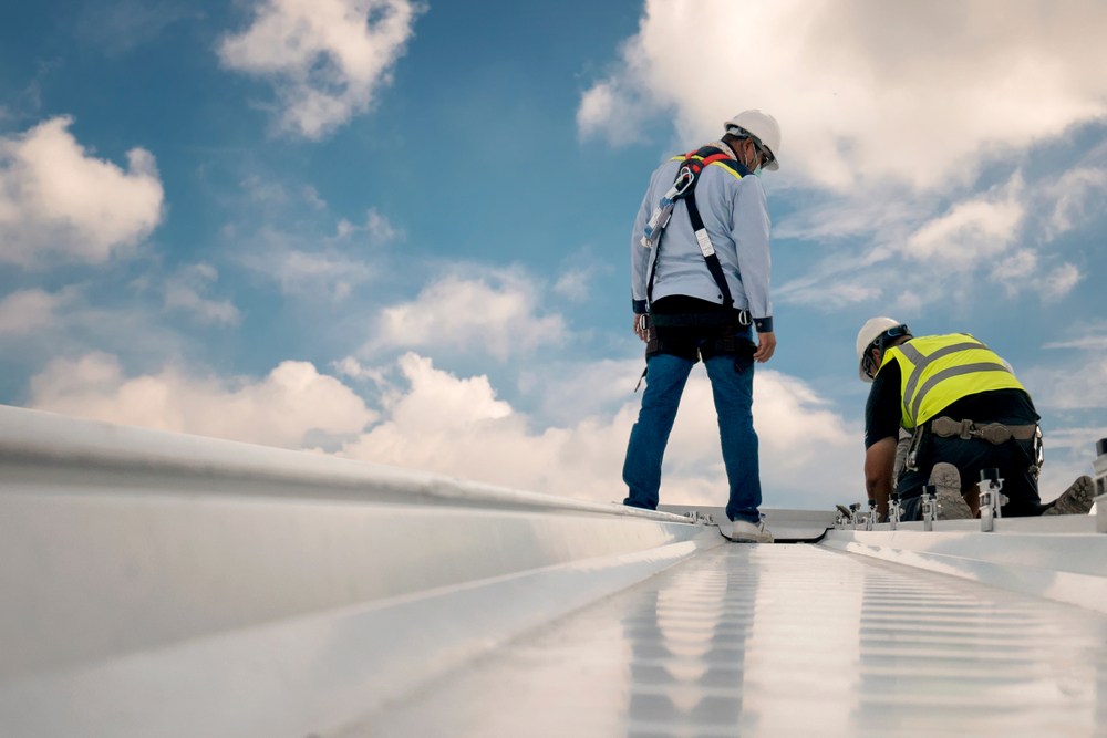 CConstruction engineers in safety uniforms inspect a roof.