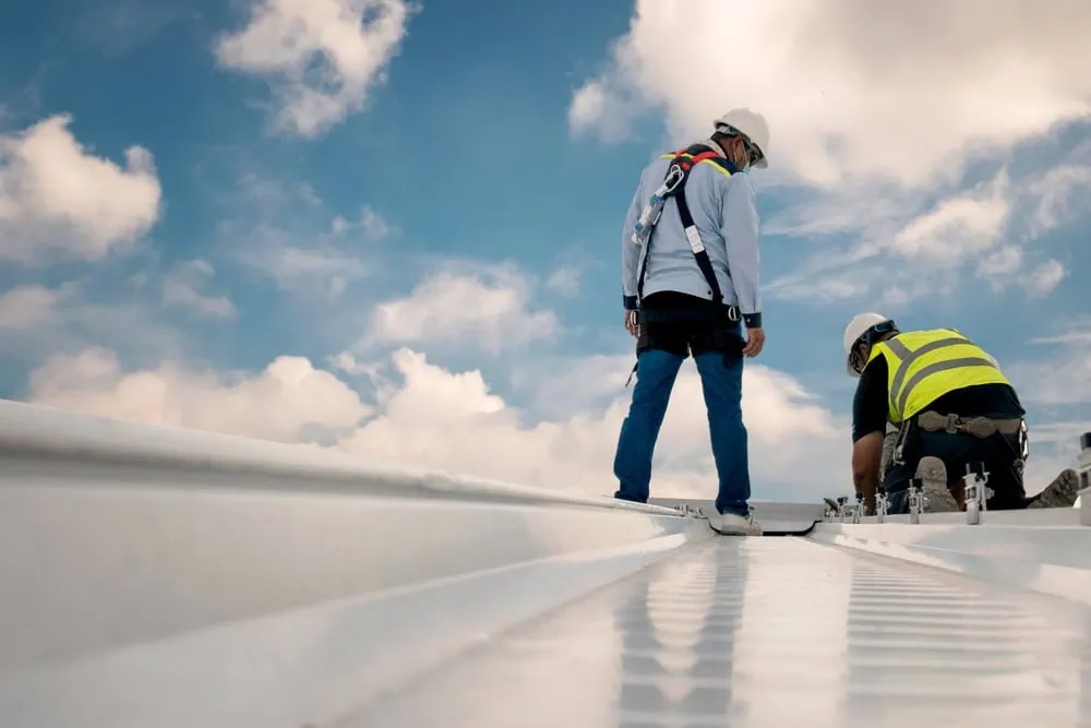 Construction engineers in safety uniforms inspect a roof.