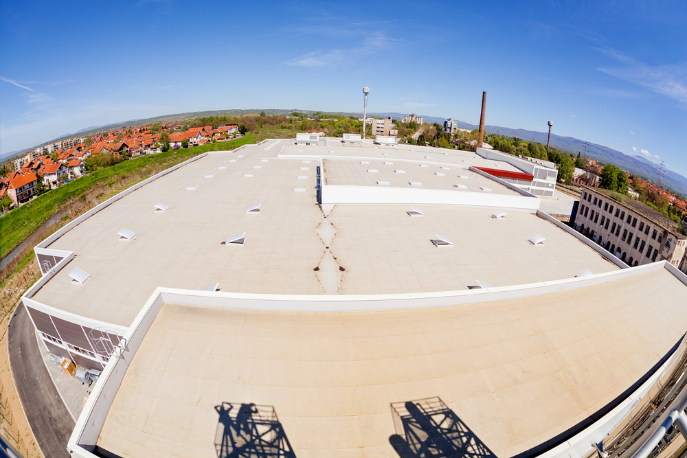 A view of a flat industrial rooftop with large windows and a ventilation system.