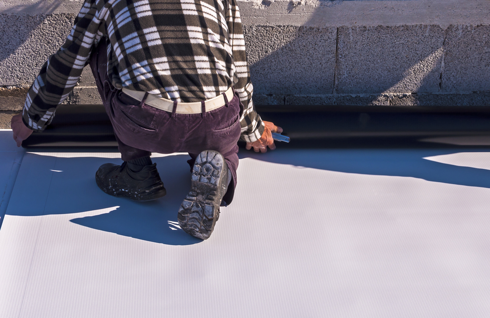 Worker applying a synthetic waterproof PVC-P membrane.