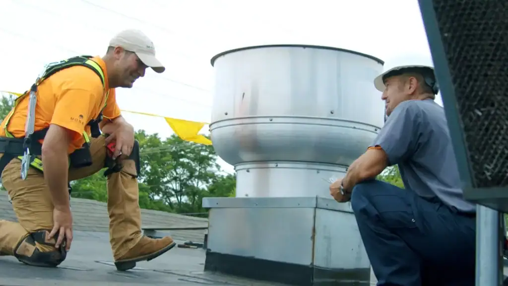 Moser Roofing team members discussing a commercial roofing project while kneeling on a flat roof