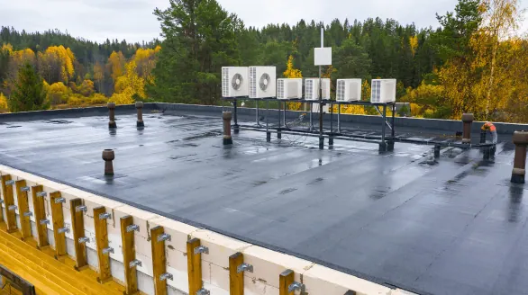 a roof with air conditioning units and trees in the background