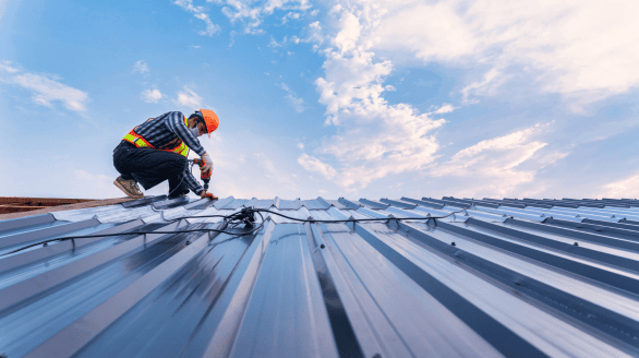 a man wearing a hard hat and holding a drill on a roof