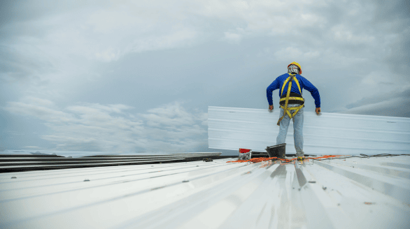 a man wearing a hard hat and safety harness holding a white sheet