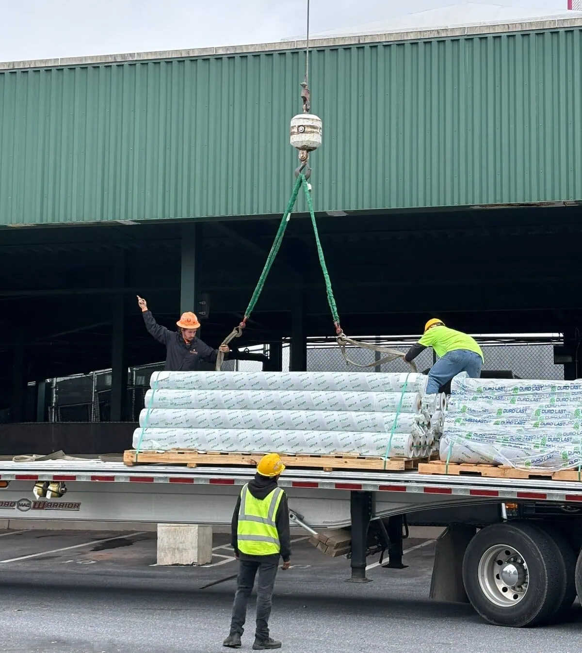 a group of men lifting a load of material for a roof replacement